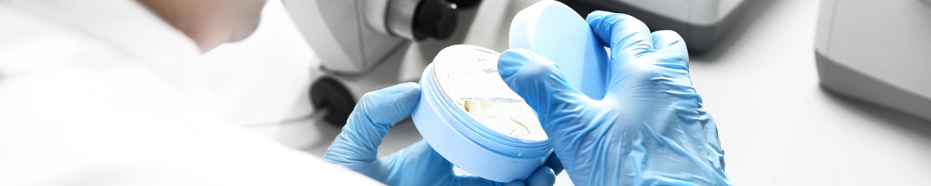 Pharmacist holding a open tube of cream in a laboratory.